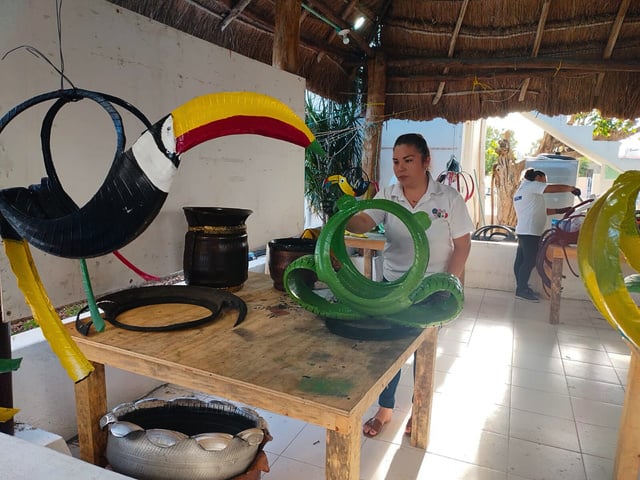 a workshop where a woman is spray painting tyres which have been reshaped into animal sculptures