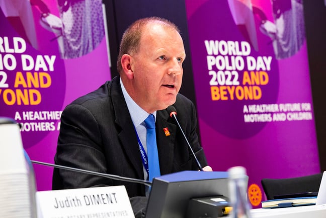 Aidan O'Leary sat in front of a microphone at a World Polio Day event
