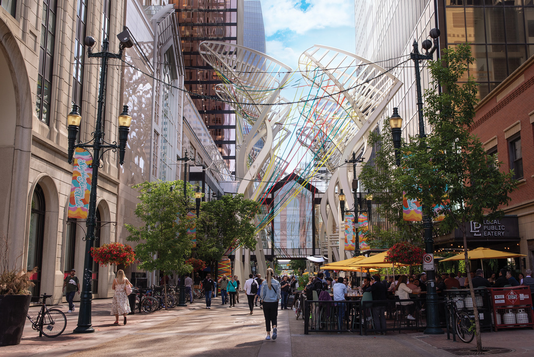 a sunny street in Calgary, Canada where people sit outside at a restaurant