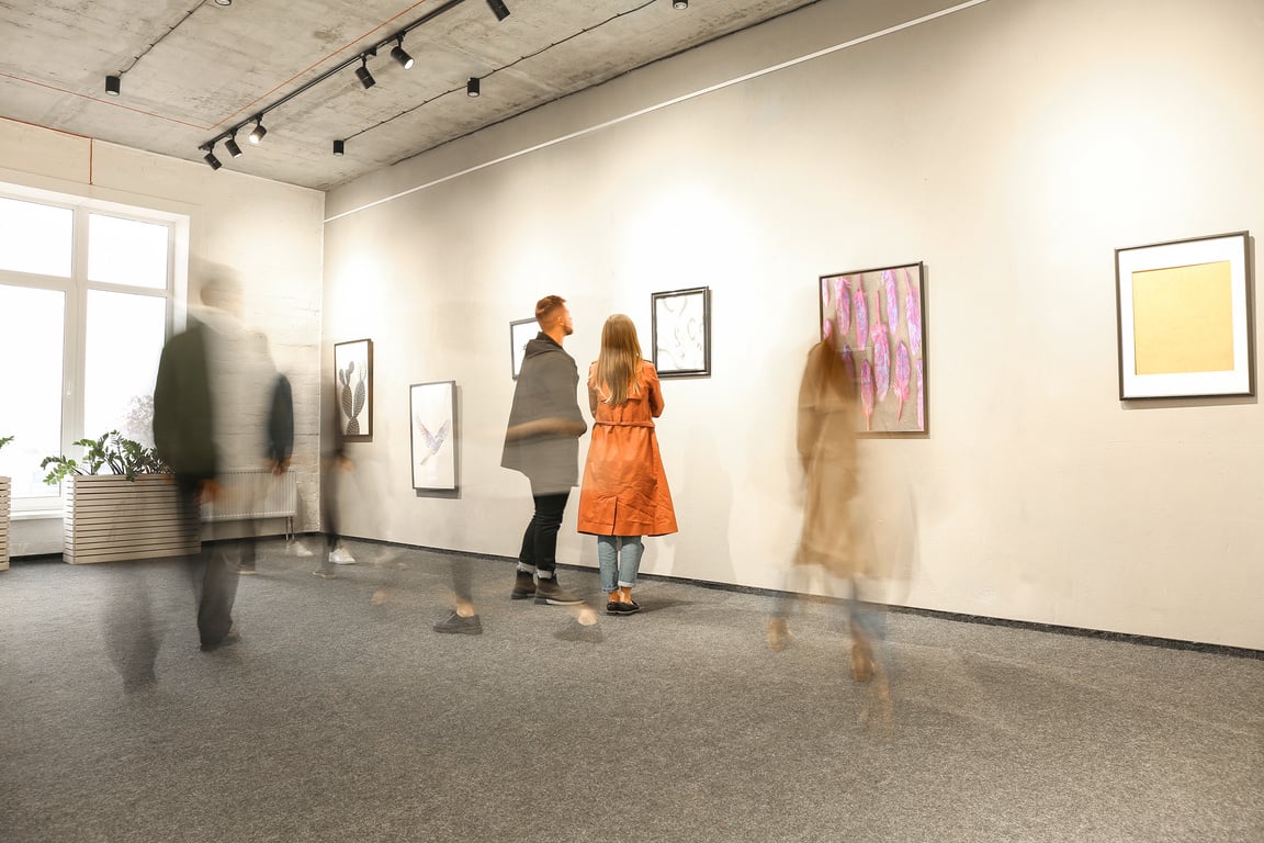 a blurry image of people walking in an art gallery