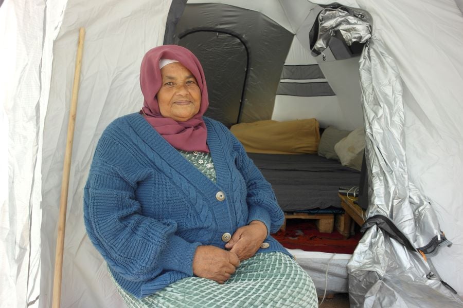 A Moroccan woman sitting in a white tent provided by Shelterbox.