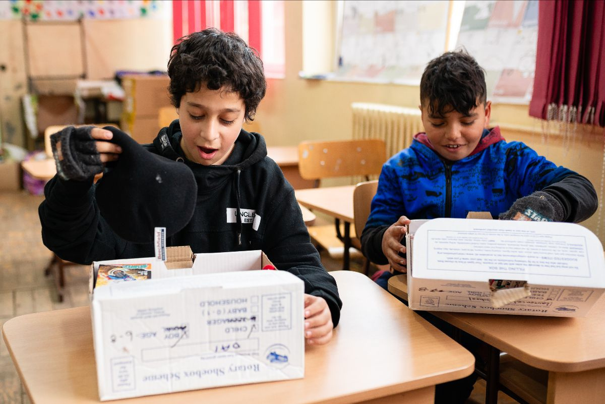 two young people smiling whilst opening their Rotary shoeboxes