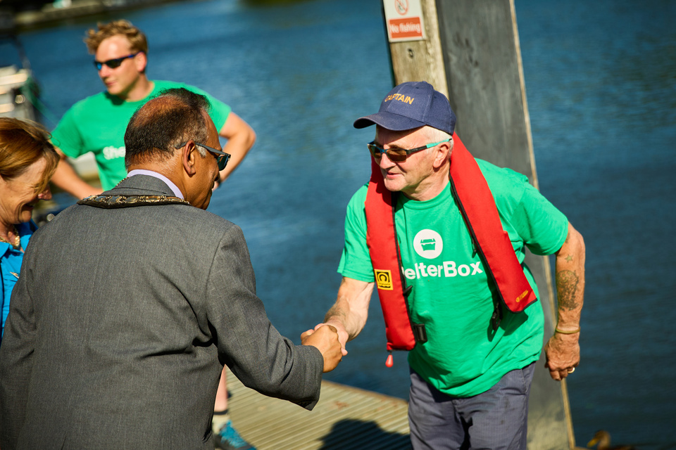 a person in a green shirt shaking hands with another person on a dock