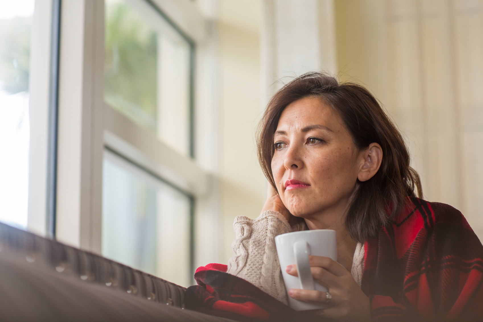 a person is looking out the window with a cup of coffee