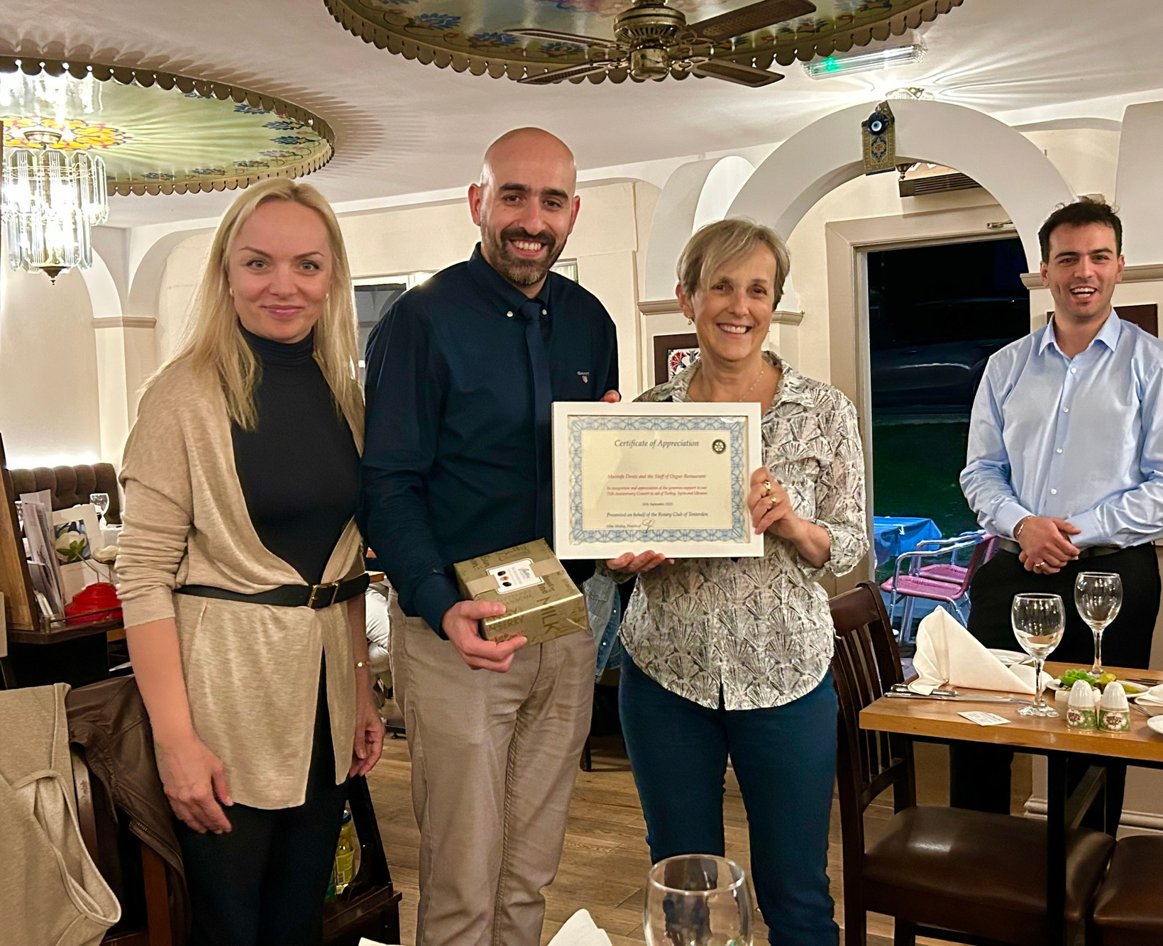 Mustafa Deniz, owner of the Ozgur Restaurant In Tenterden, receives a certificate of thanks from Tenterden Rotarians Oksana Romanukha and Emma MacLennan. 