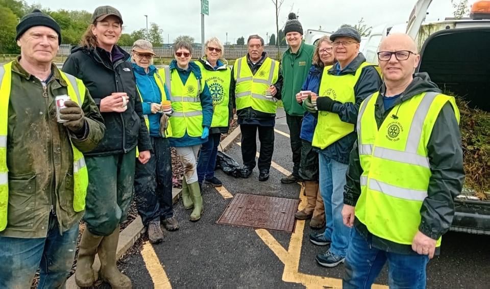 A group of Rotarians in yellow vests standing next to a truck.