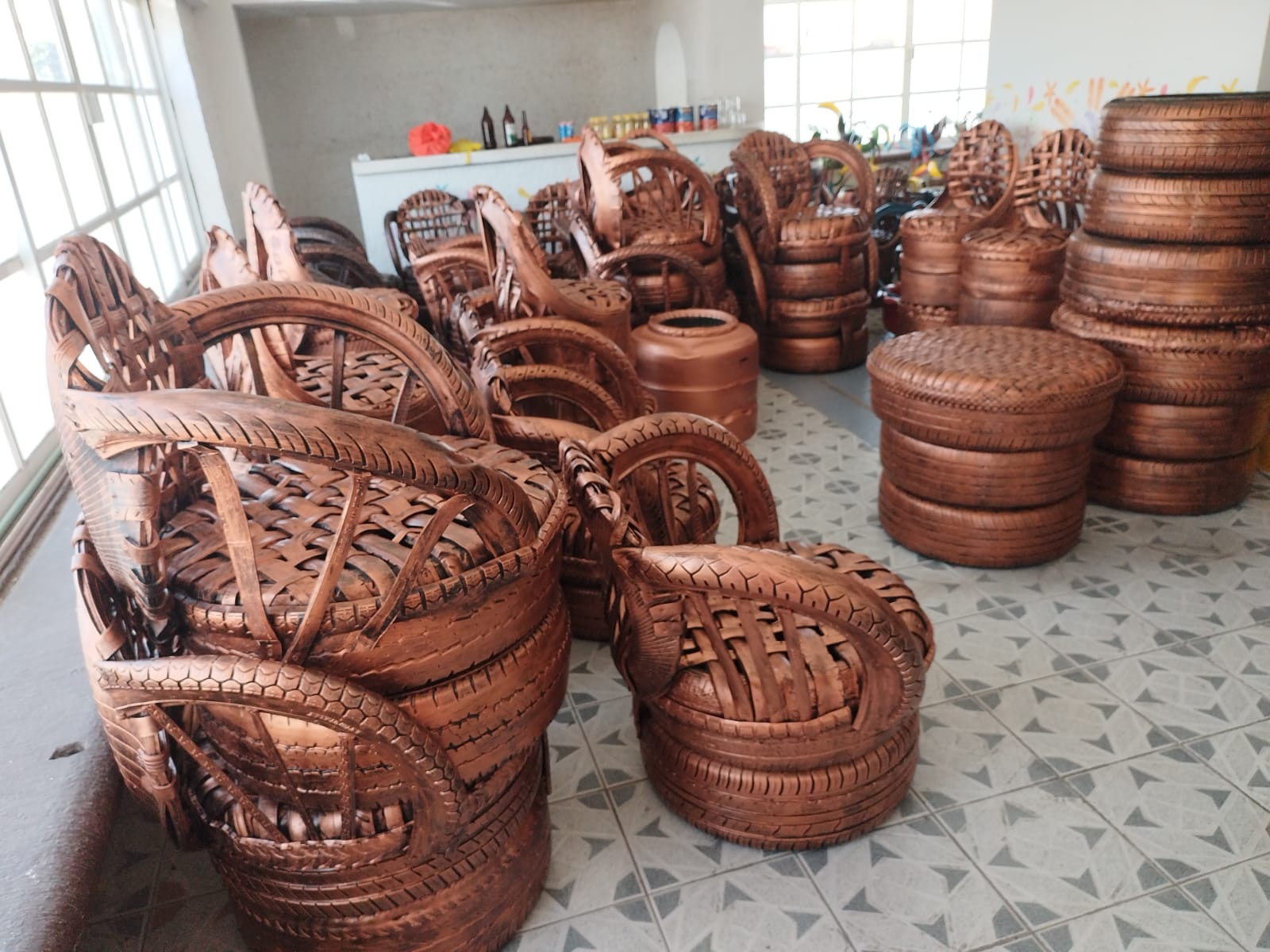 A selection of tyres which have been cut and reshaped into chairs and footstools and painted brown