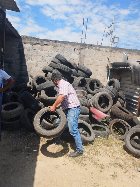 a man stacks old tyres into a pile in a junkyard