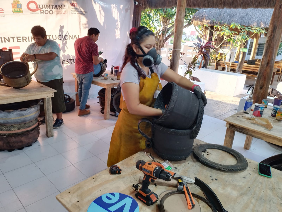 a person in a yellow apron is working on reshaping a tyre