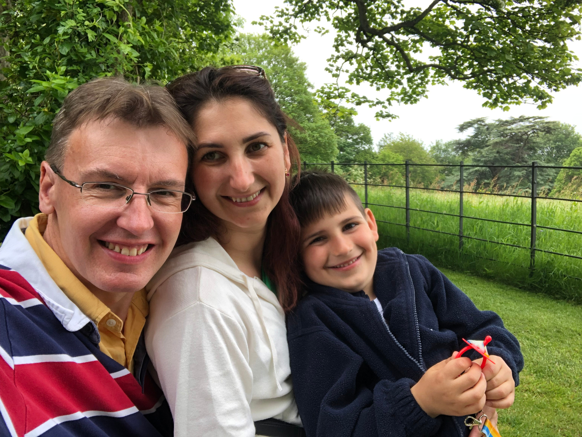 a man, woman and child pose for a photo in the grass