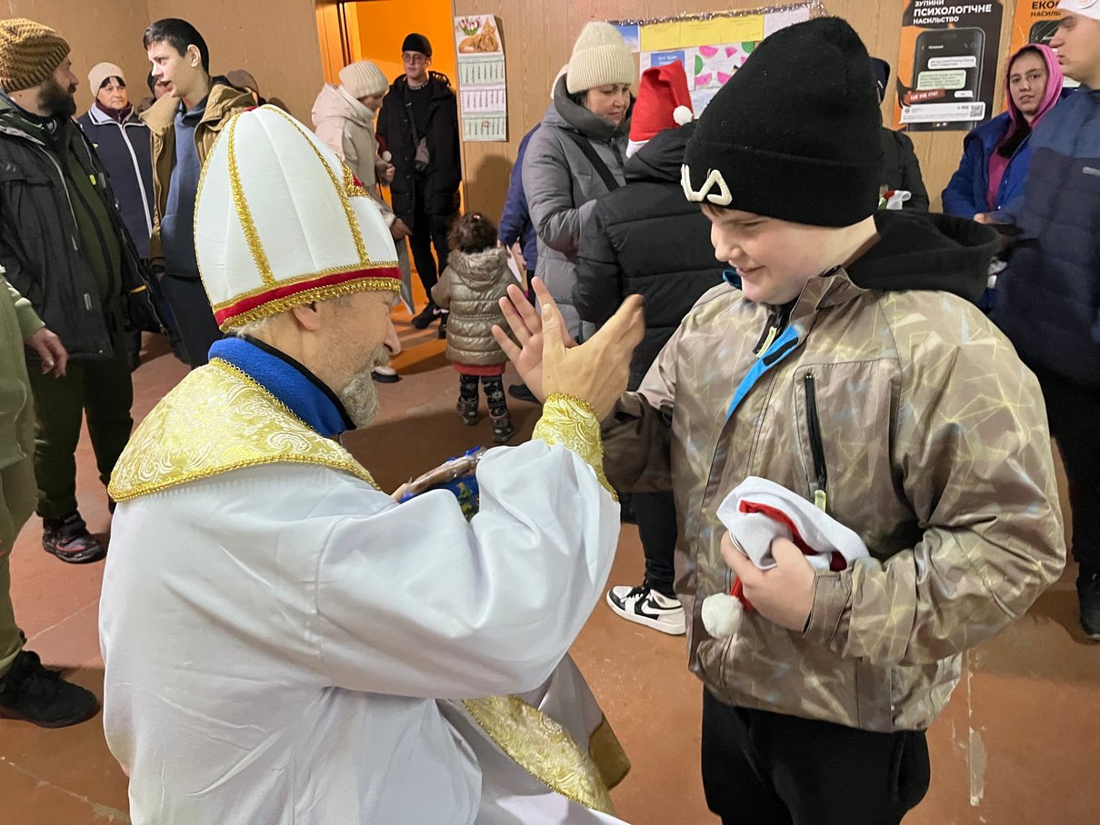 A Rotarian dressed as Saint Nicholas gives a child a high-five.