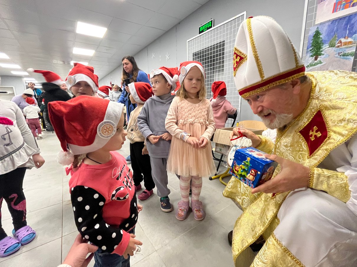 A Rotarian dressed as Saint Nicholas is talking to children at a Christmas party.