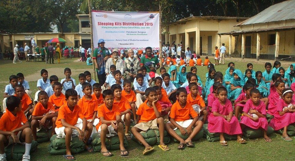 a group of children in orange shirts sitting on the grass