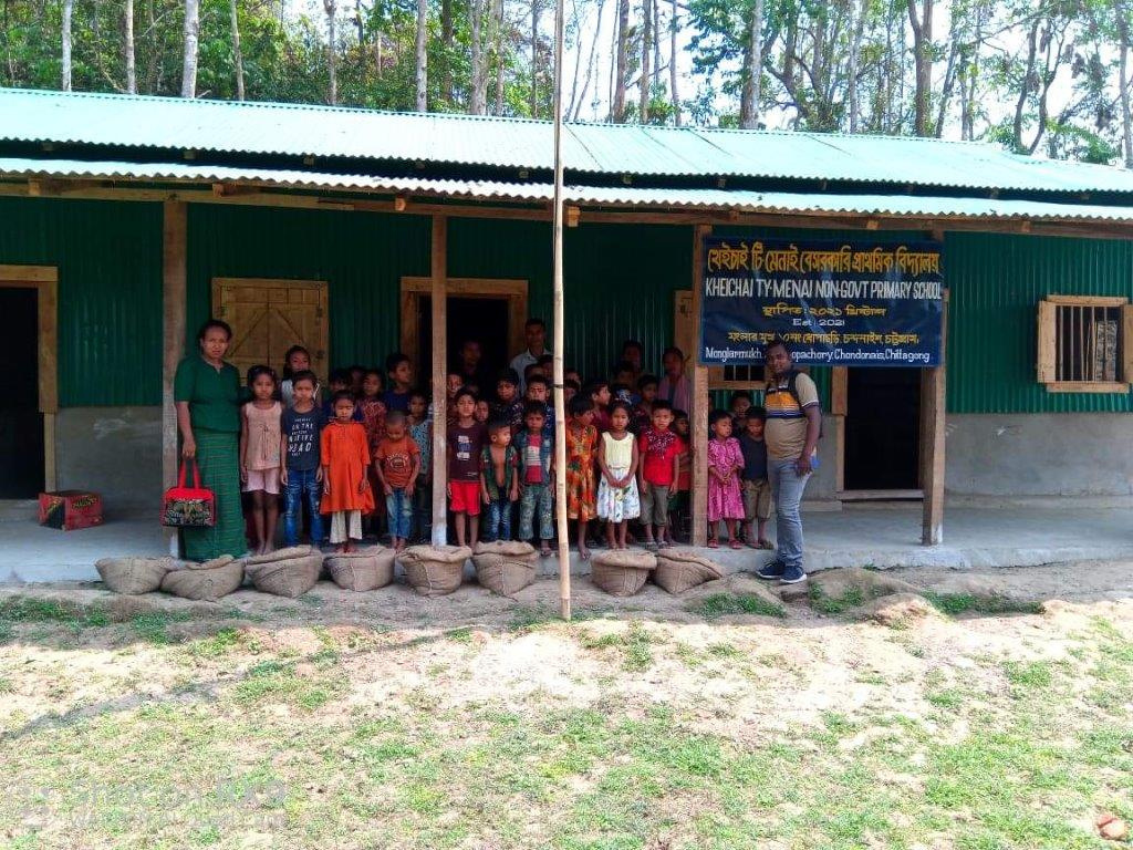 a group of children standing in front of a school building in Bangladesh