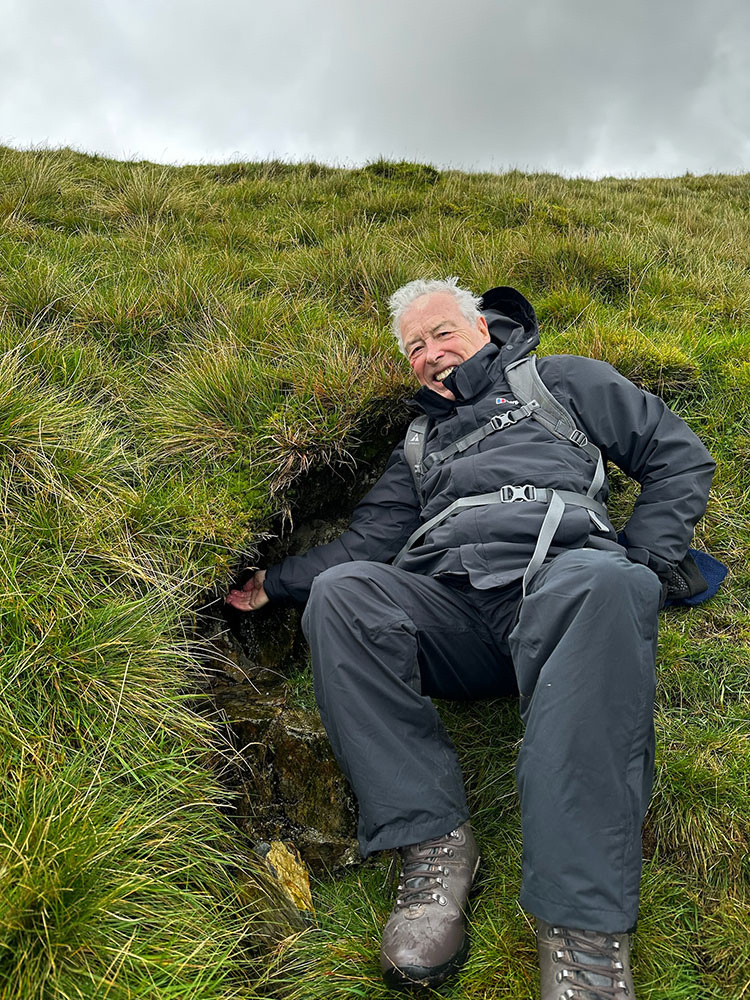 A person sitting in a hole in the grass.