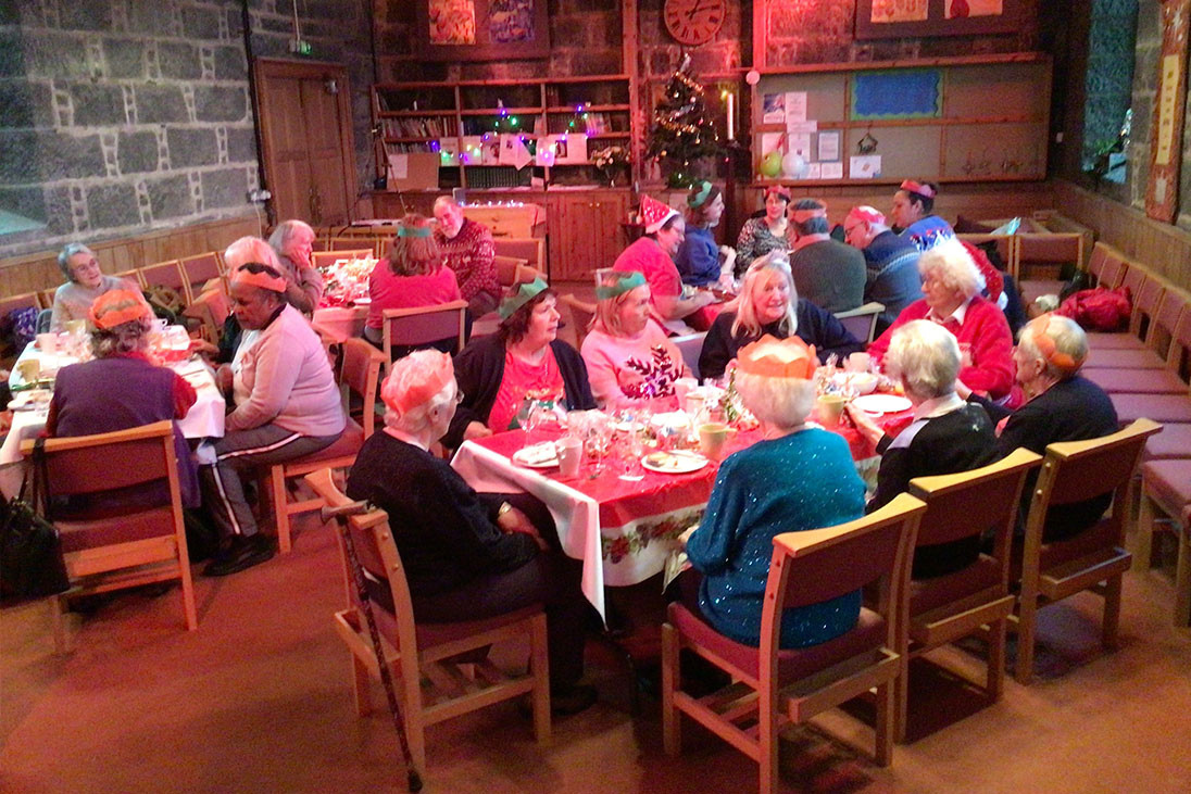 a group of people sitting at tables wearing Christmas hats